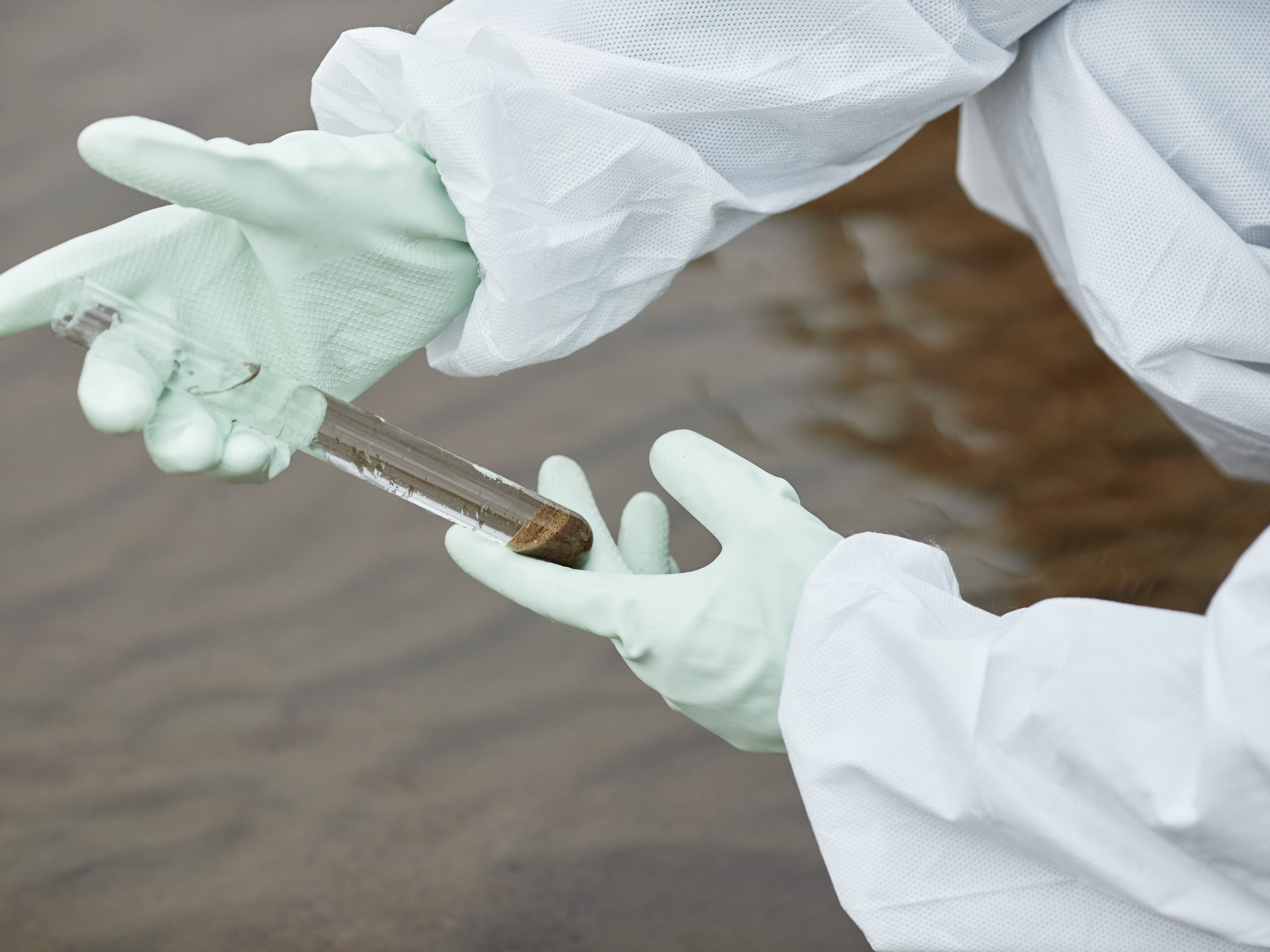 Scientist holding test tube sample containing water. 