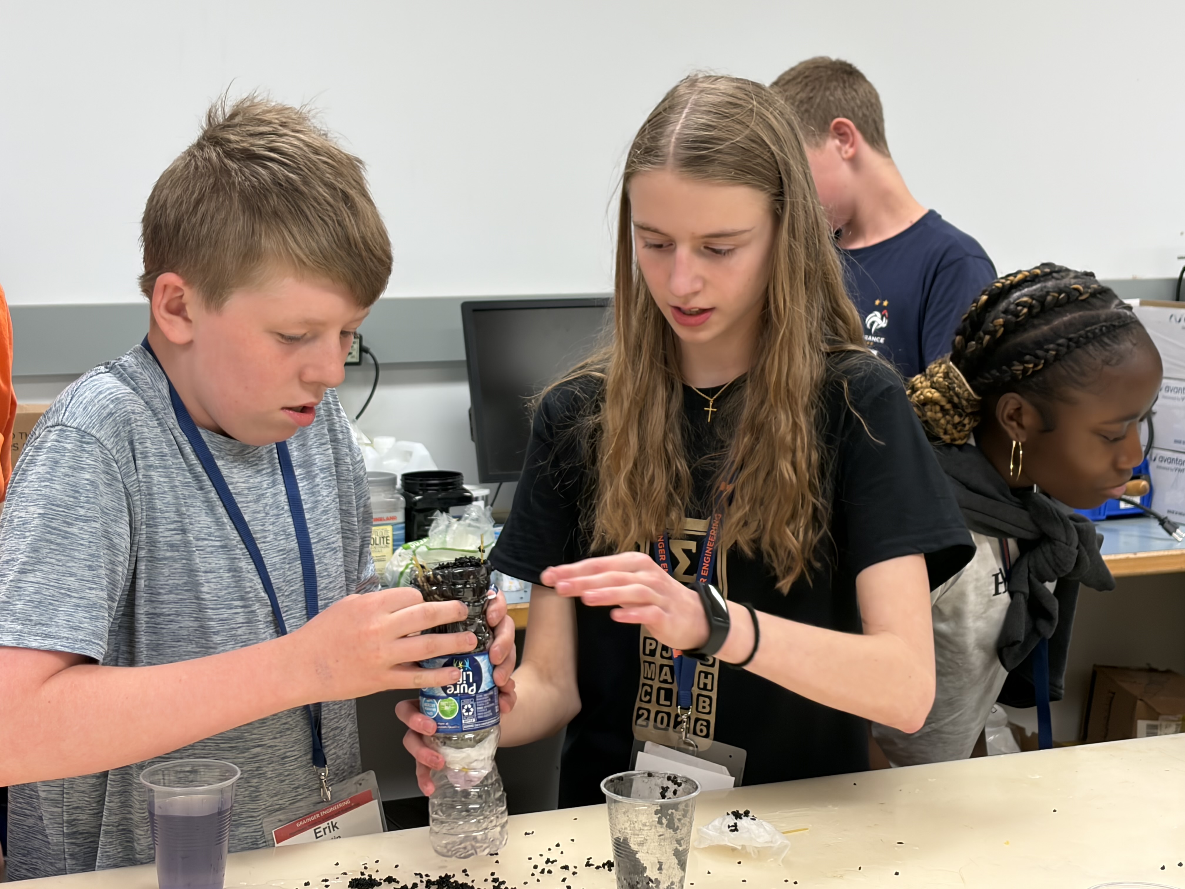 Two students work together on a water filtration project using plastic water bottles during the 2026 edition of Mid-GLAM camp.