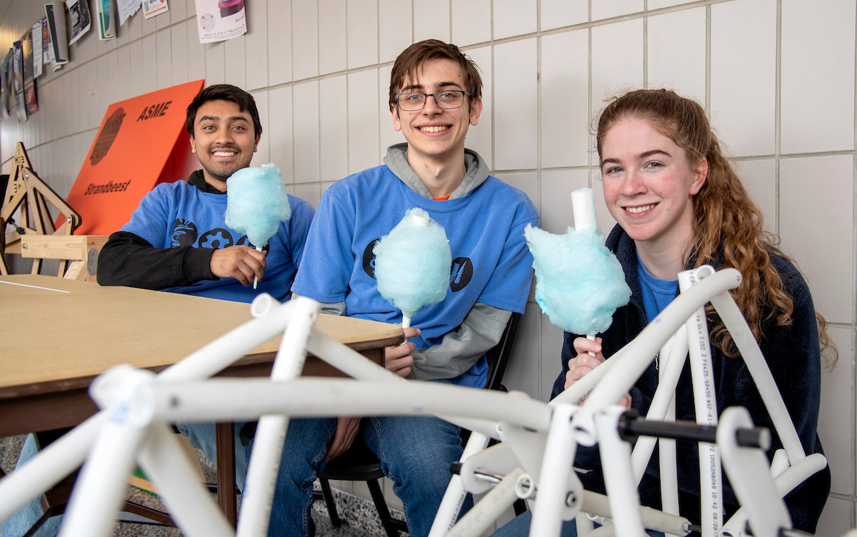 Heather Coit/The Grainger College of Engineering<br>MechSE students are all smiles holding cotton candy made by MatSE students at the Loomis Lab during Engineering Open House on April 8.