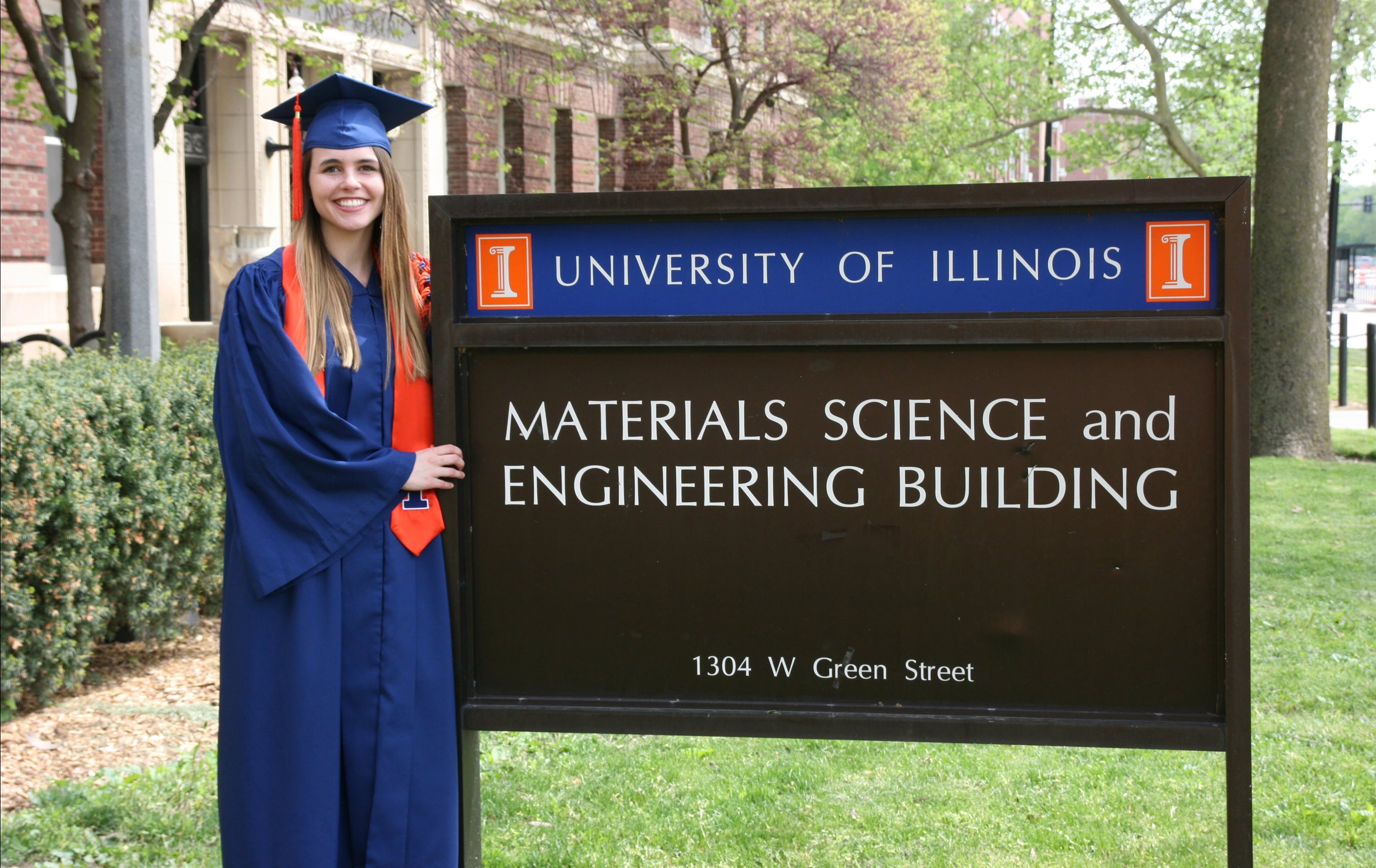 Lauren (Smith) Fey, an '18 MatSE alumnus and now computational researcher and doctoral student at the University of California, Santa Barbara, is all smiles in her graduation regalia outside the Materials Science and Engineering Building on Green Street in Urbana, Ill.