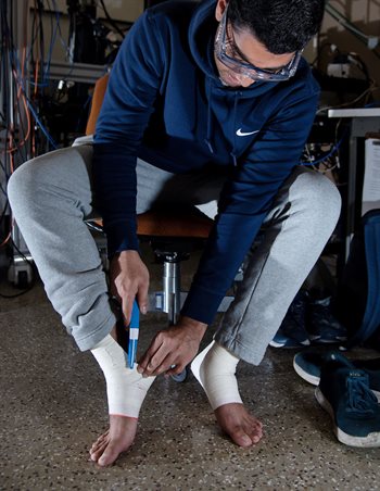 Suhaas Reddy cuts the athletic tape off his ankle for the team to conduct analysis on it in the Talbot Lab in Urbana, Ill. earlier in April.