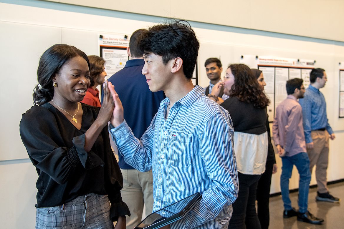 MatSE seniors Ibukun Ajifolokun, left, and Yu-Chang Chen give each other a high five ahead of their senior project presentation during the annual presentation day held at the Campus Instructional Facility in Urbana, Ill. on May 5.