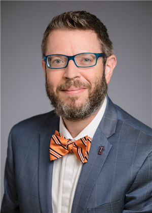 Man in suit with bow tie smiles at camera